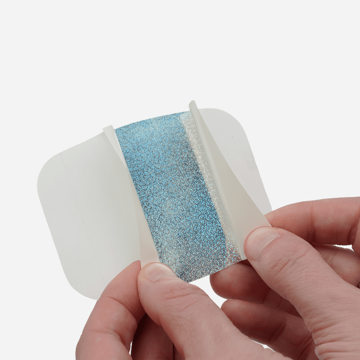 Close up of hands peeling the split backing on a custom glitter sticker for easy, bubble-free application.
