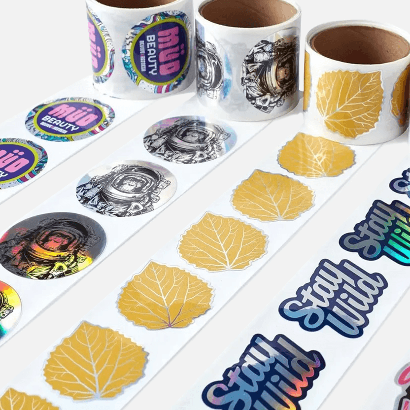 Holographic sticker rolls featuring custom logo designs printed on perforated rolls for promotions, branding, and product packaging.