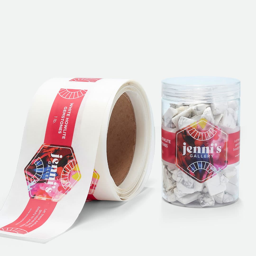 Clear roll labels applied to a gemstone container shown beside a roll of custom clear labels.