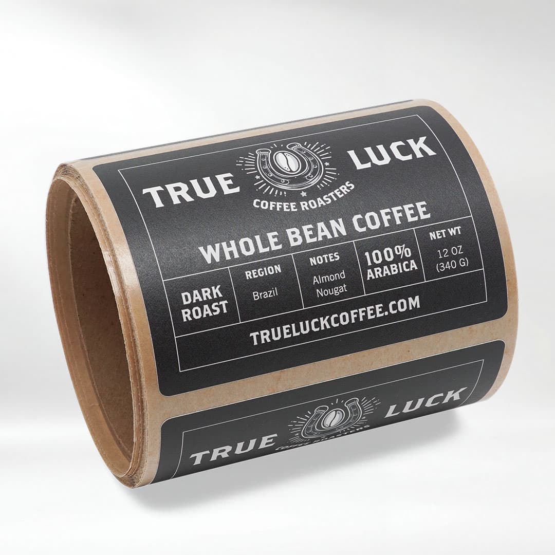Roll of True Luck Coffee recycled matte paper labels with a kraft paper backing for premium coffee packaging.
