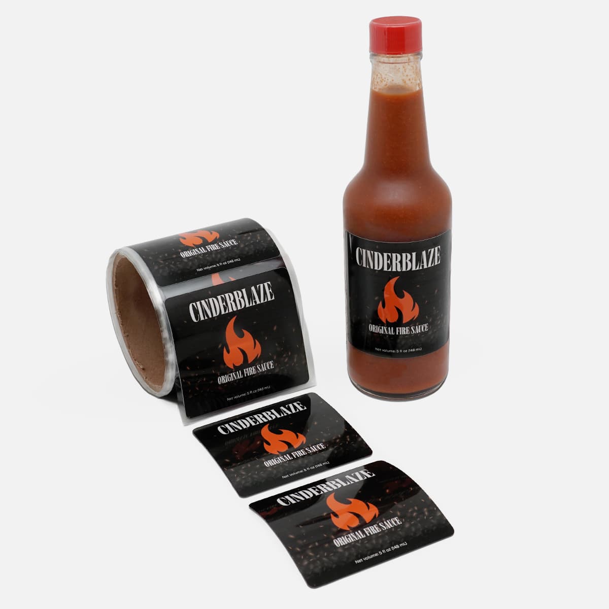 Custom PET Backing bottle labels applied to a hot sauce bottle with a roll of matching product labels for retail packaging.