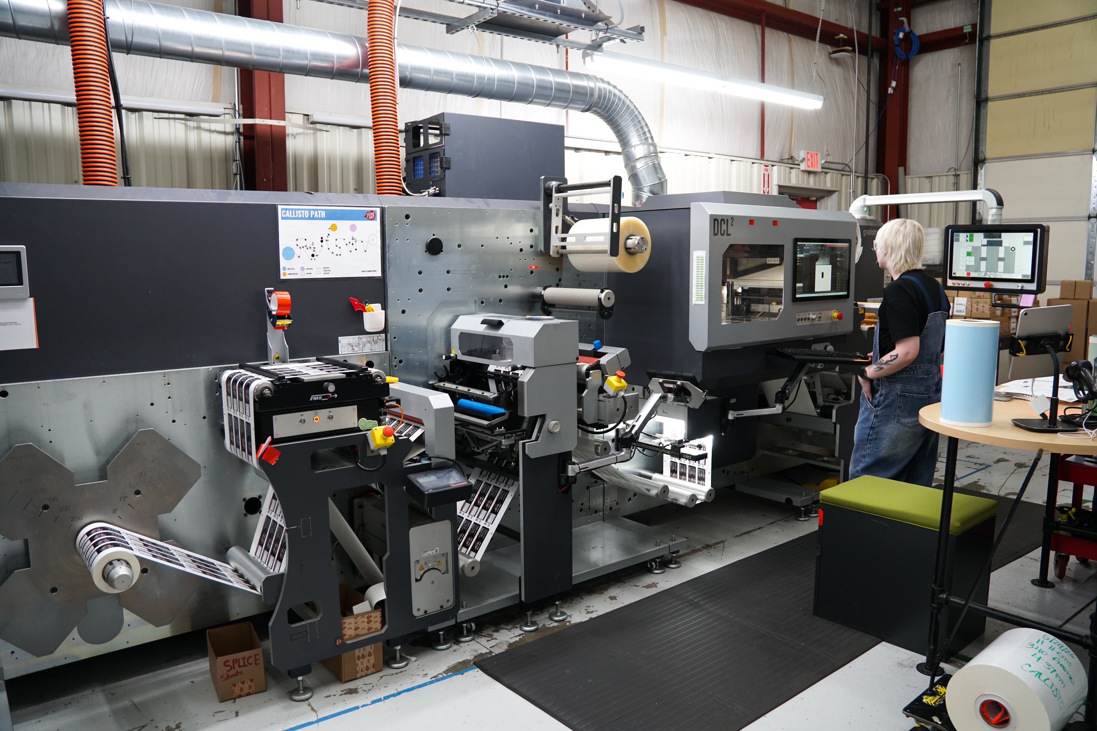 Employee operating a digital sticker printing press in StickerGiant's production facility.