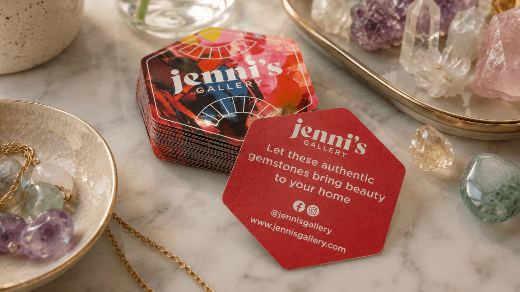 Backprinted gemstone brand stickers displayed with crystals and jewelry on a marble counter.
