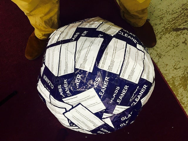 Top-down view of a partially built sticker ball covered in overlapping product stickers.