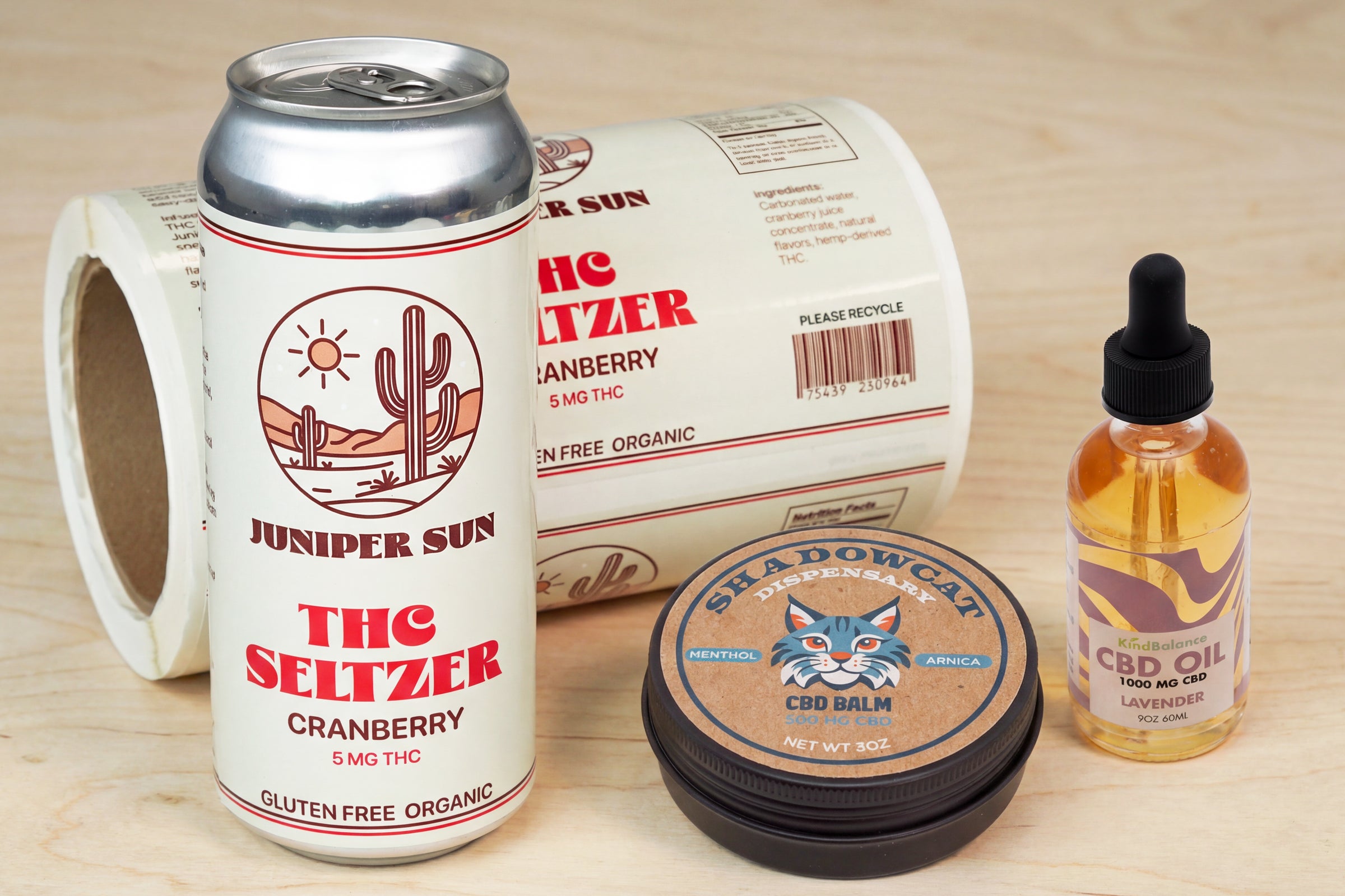 Editorial image of cannabis product labels on beverage can, CBD balm, and CBD oil packaging.