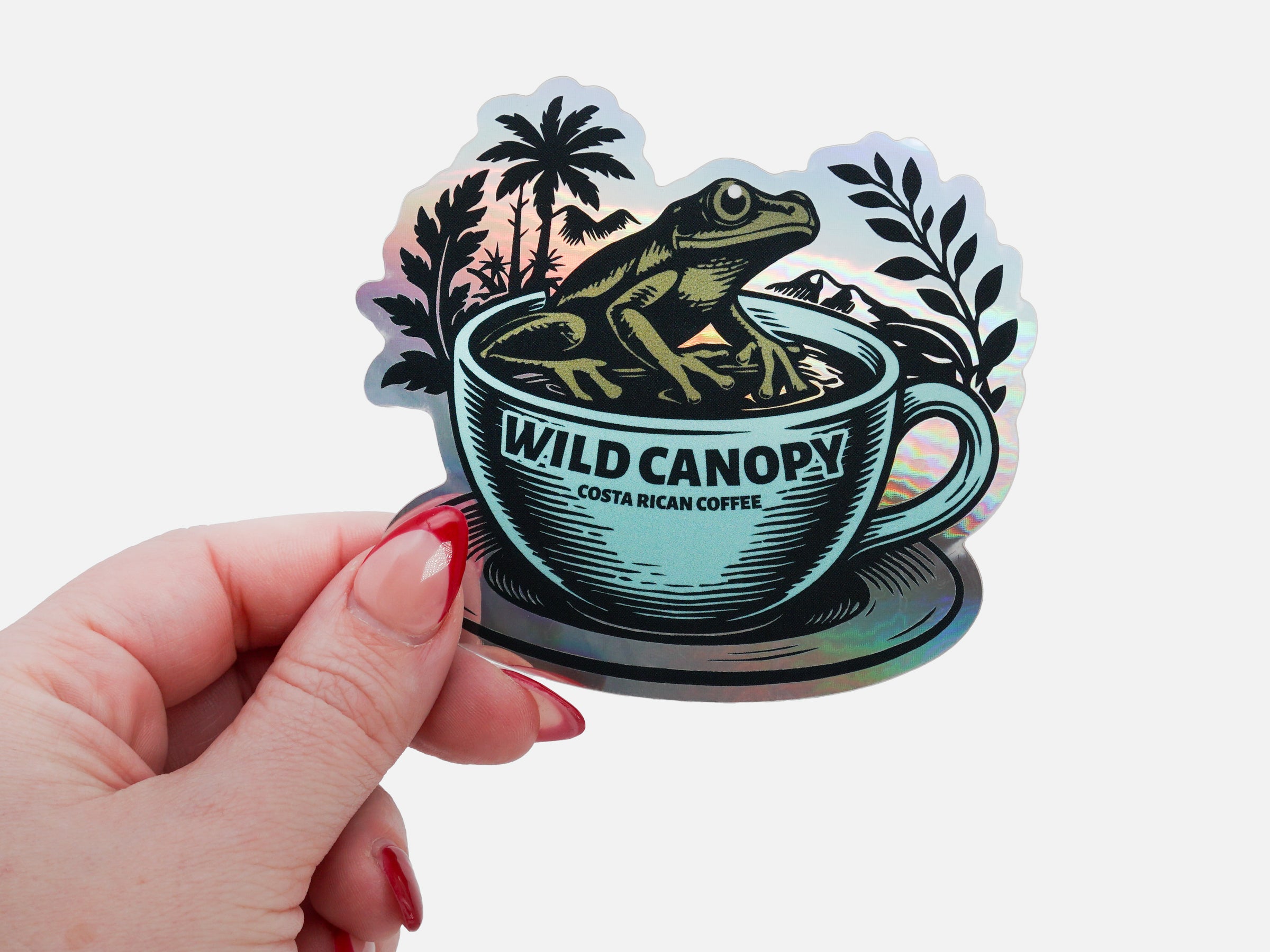 Holographic coffee brand sticker held in hand with illustrated frog design.