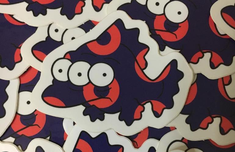 A group of die-cut stickers featuring a cartoon three-eyed fish character in dark purple with red donut-shaped markings.