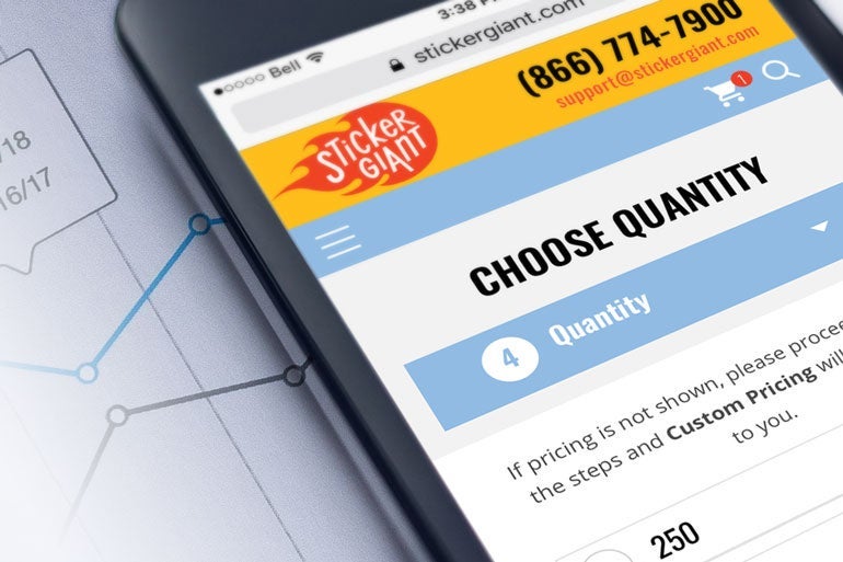 Mobile phone displaying the StickerGiant website with a quantity selection screen, shown against a background of analytics charts.