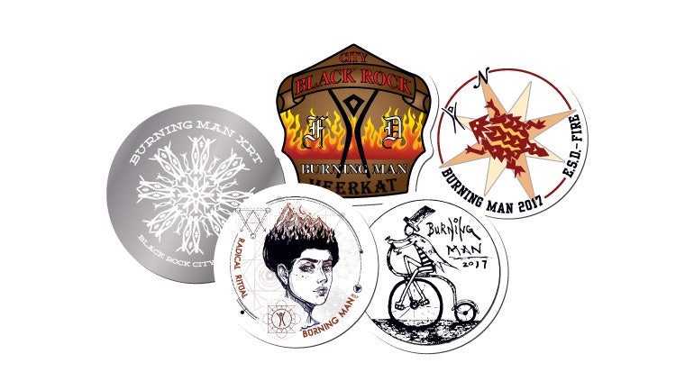Collection of custom Burning Man stickers featuring artistic designs, symbols, and event-inspired illustrations.