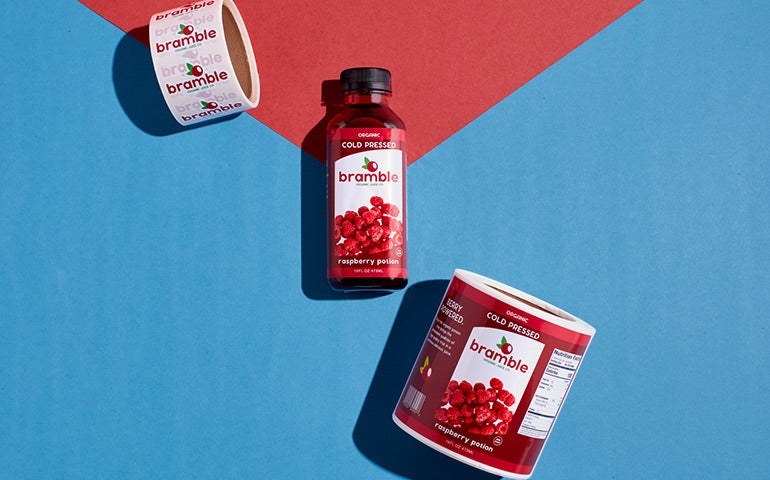 Bramble juice bottle with matching custom labels and rolls on a colorful background.