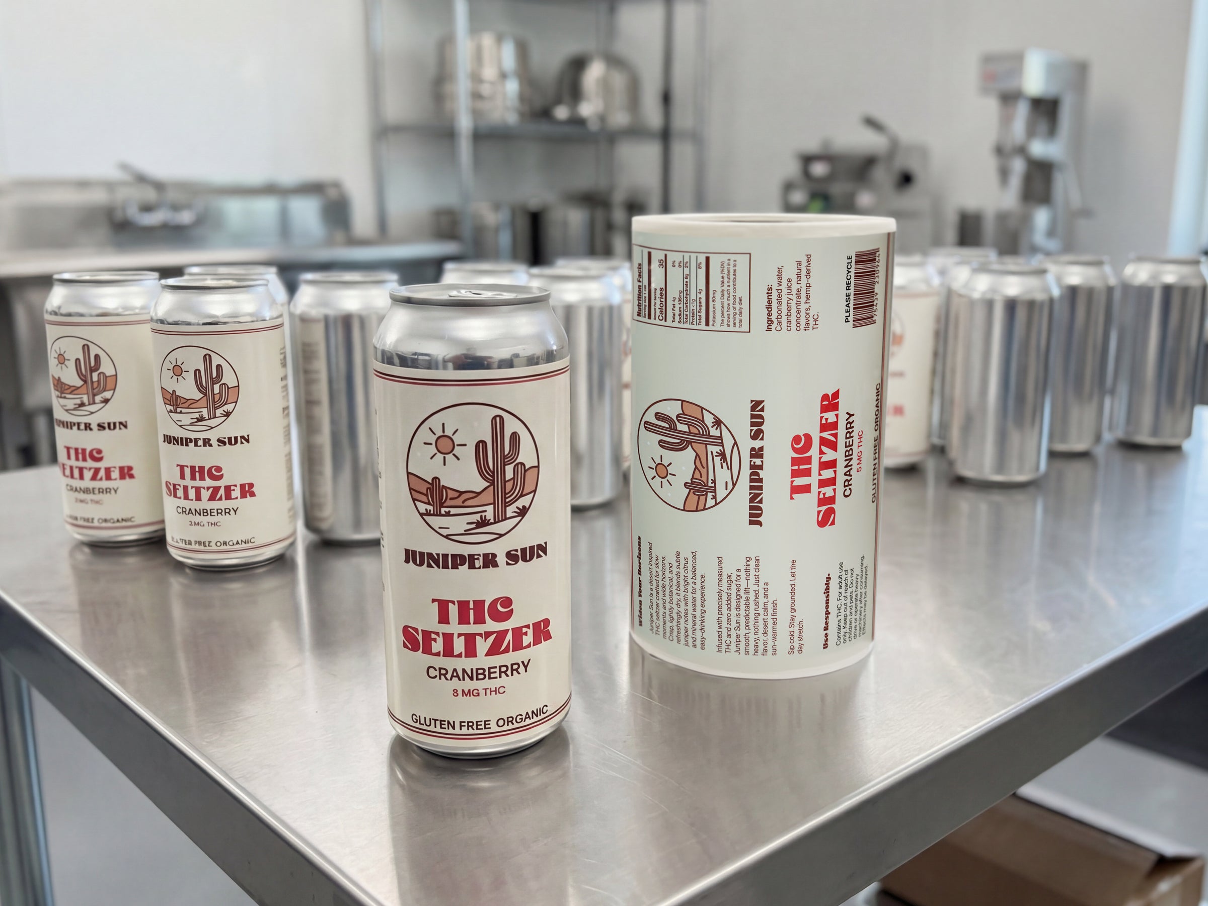 THC seltzer cans with beverage labels and printed label roll.