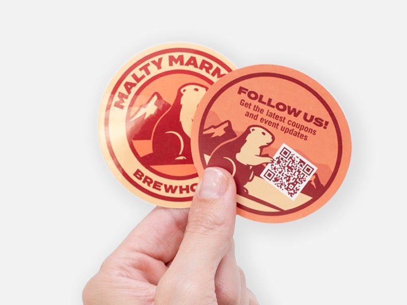 Backprinted brewery sticker with QR code for social media promotions held in hand.