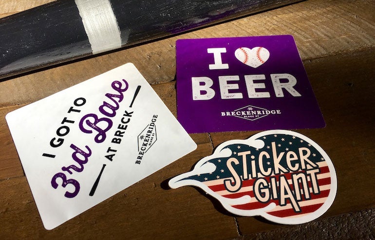 Three custom stickers displayed on a wooden surface, including two Breckenridge Brewery stickers and a StickerGiant logo sticker.
